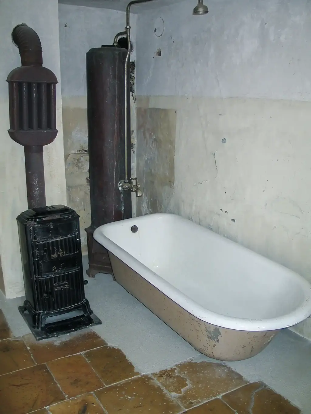 Ein einfaches Badezimmer mit Badewanne und alten Heizgeräten.