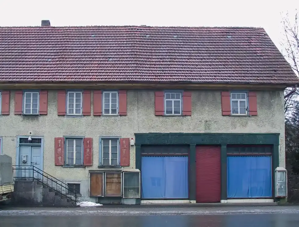 Ein altes Gebäude mit großen Schaufenstern und roten Fensterläden.