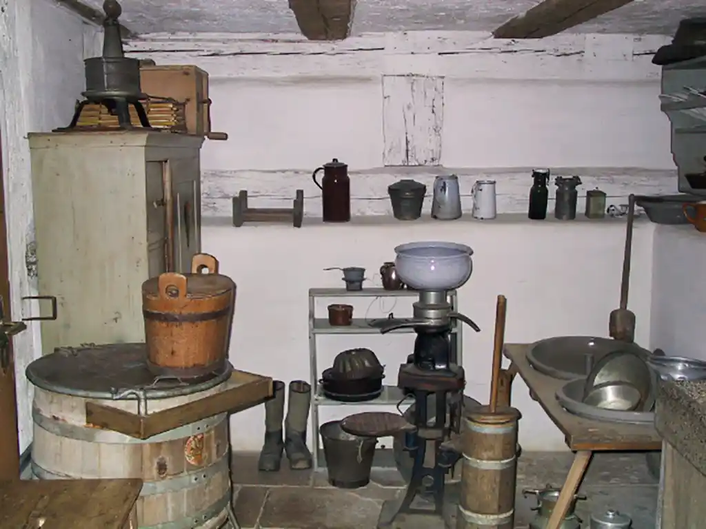 Alte Küche mit rustikalen Holzmöbeln und Kochutensilien.