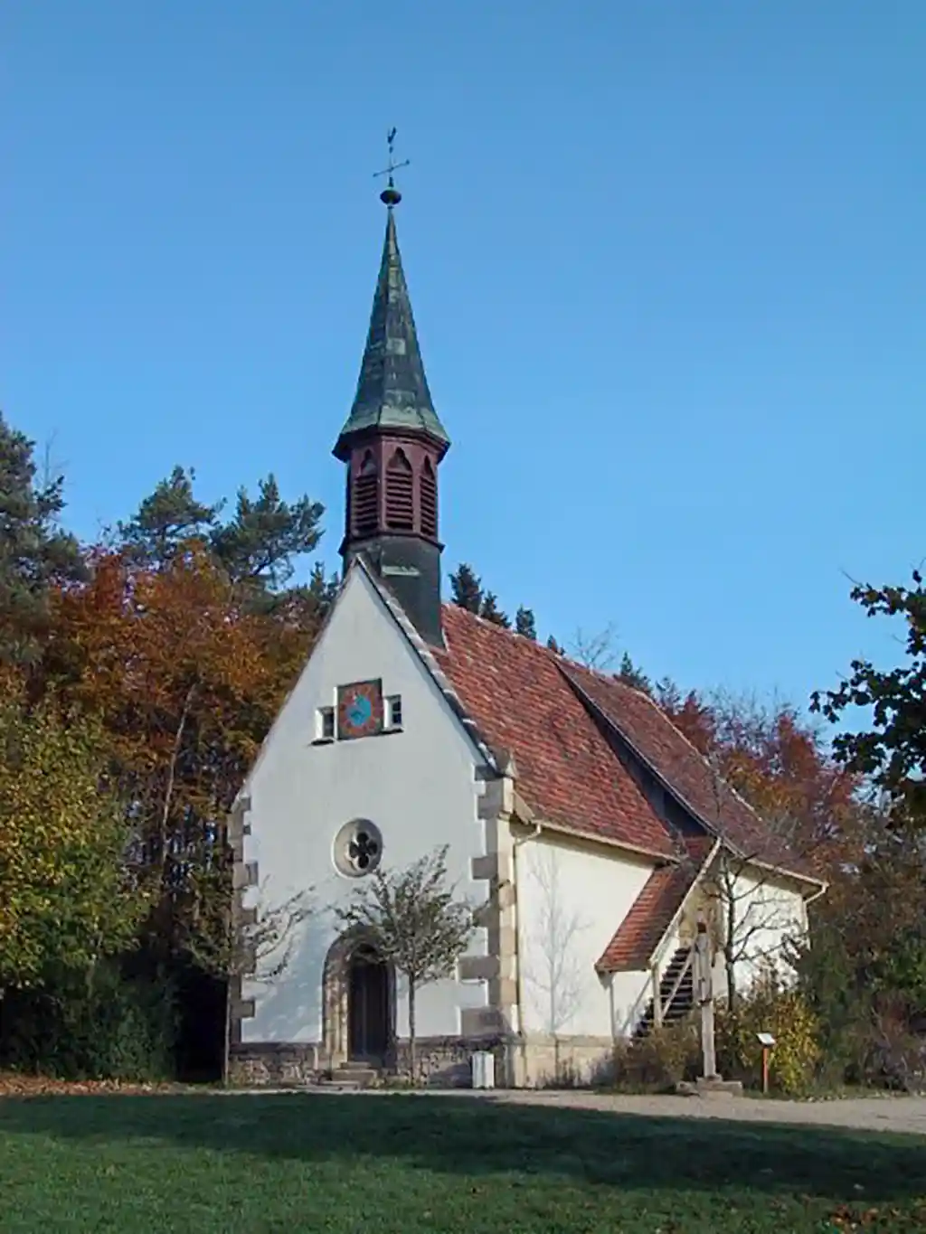 Frontale Ansicht der Dorfkirche Tischardt mit Eingangstür, rundem Kirchenfenster und Kirchturm.