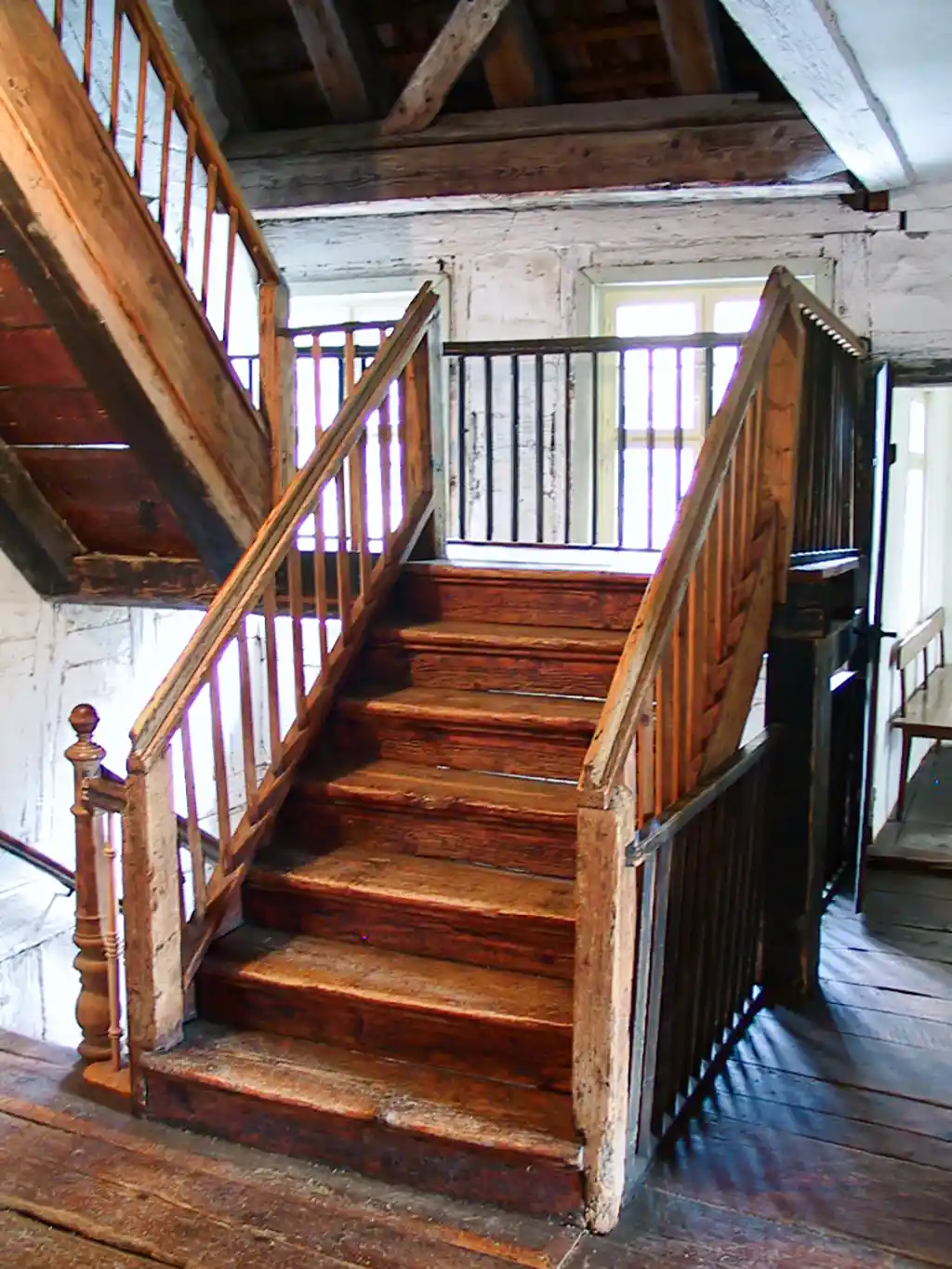 Holztreppe mit Geländer, die ins obere Stockwerk führt.