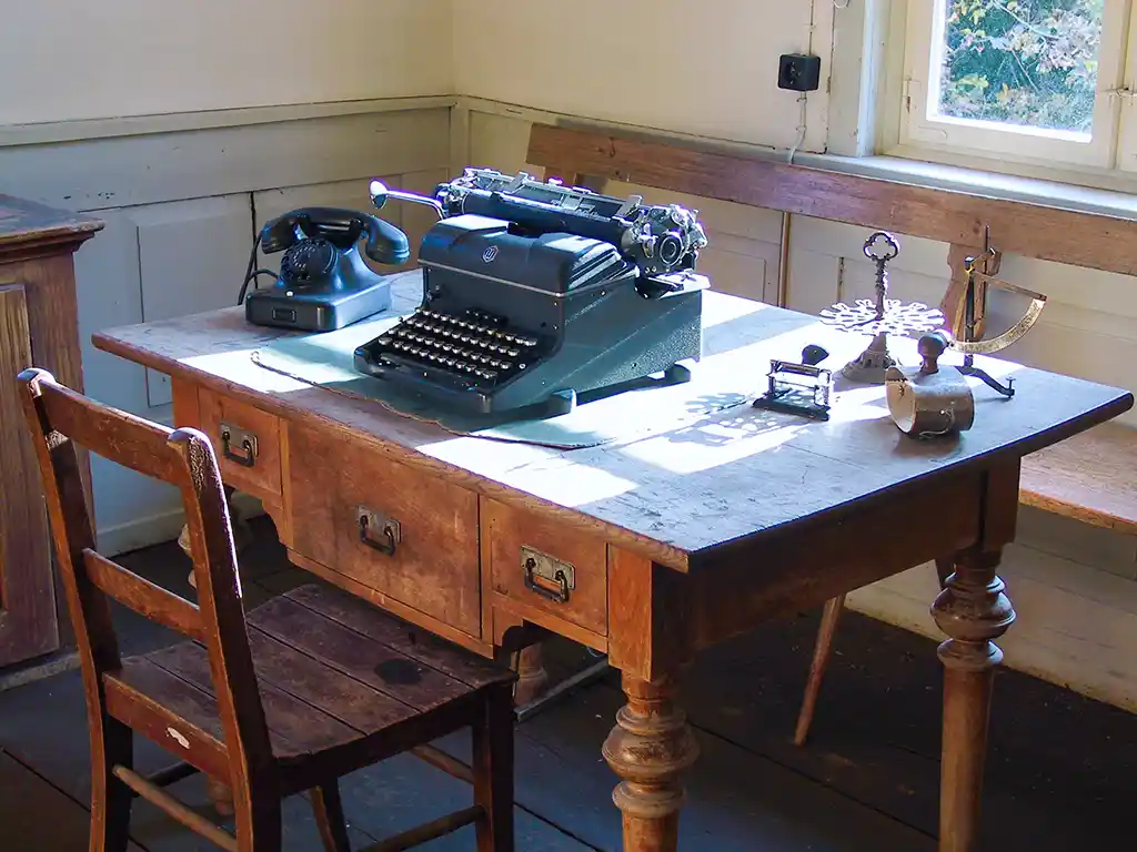 Schreibzimmer mit Holzschreibtisch, Schreibmaschine und Telefon im Schul- und Rathausgebäude.