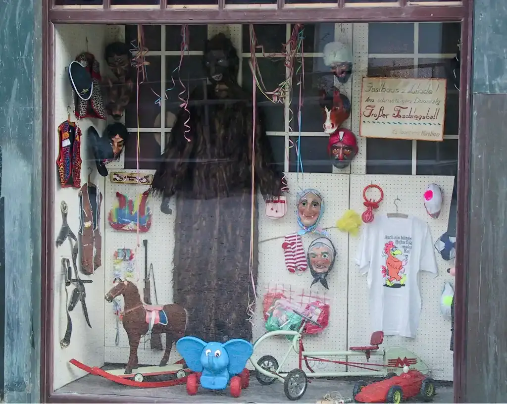 Ein dekoriertes Schaufenster mit traditionellen Faschingskostümen und Spielzeug.