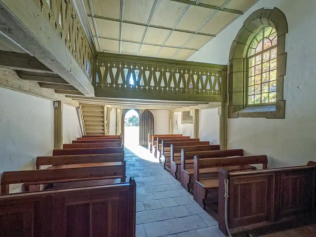 Innenansicht der Dorfkirche Tischardt vom Alter aus, Blickrichtung Eingang mit hölzernen Kirchenbänken.